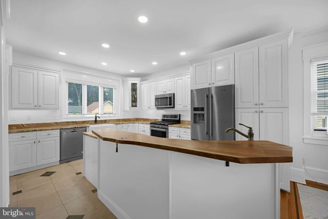 a kitchen with stainless steel appliances granite countertop a refrigerator a sink a stove a dining table and chairs