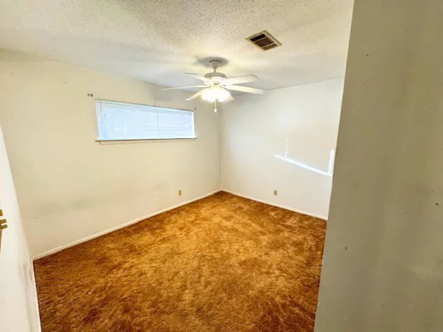 an empty room with a ceiling fan and a window