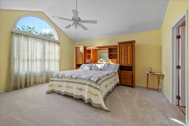 a spacious bedroom with a bed a chandelier and a large window