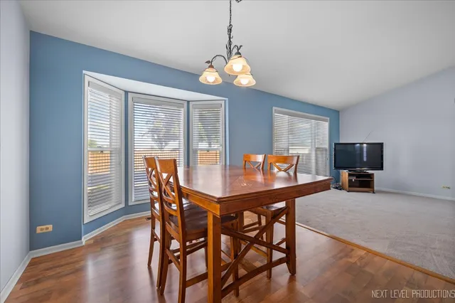 a dining room with wooden floor a chandelier a wooden table and chairs