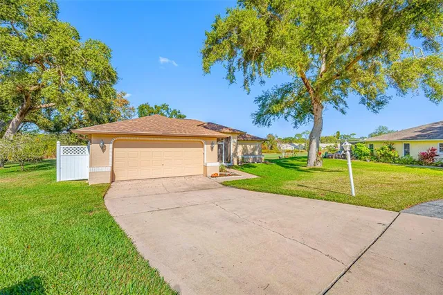 a view of a house with a small yard and a large tree