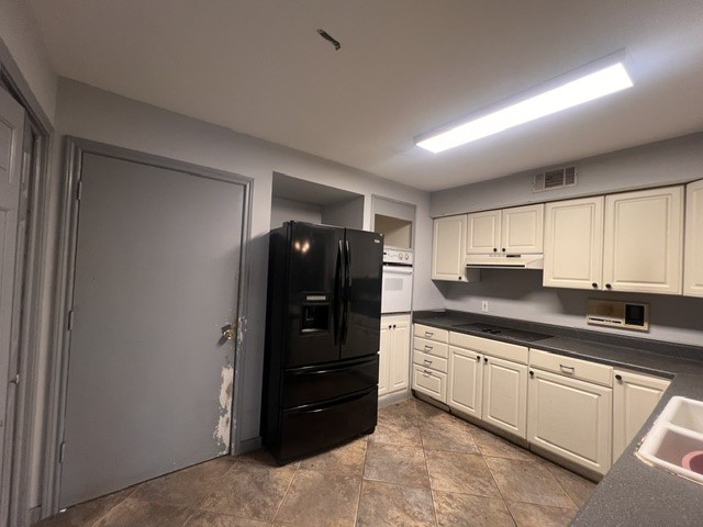 6304 South Rice Avenue Bellaire, TX 77401 - Photo 2 of 16 a kitchen with granite countertop a refrigerator and cabinets