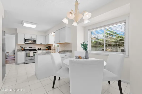a kitchen with stainless steel appliances kitchen island granite countertop a sink a stove a dining table and chairs