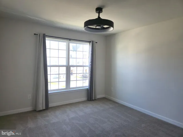 a view of an empty room with a window and a ceiling fan