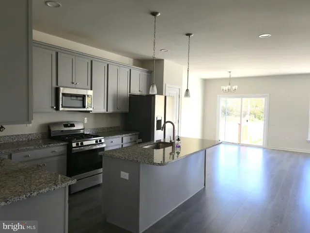 a kitchen with kitchen island granite countertop a stove refrigerator and microwave