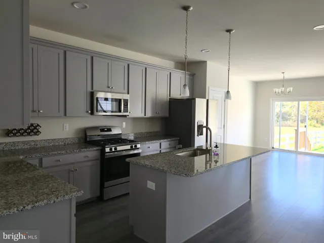 a kitchen with stainless steel appliances granite countertop a refrigerator a stove a sink a microwave and wooden cabinets