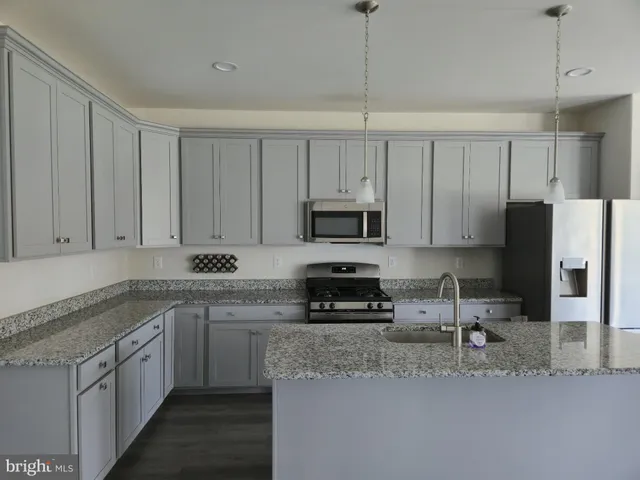 a kitchen with stainless steel appliances granite countertop a sink a stove a refrigerator cabinets and a counter top