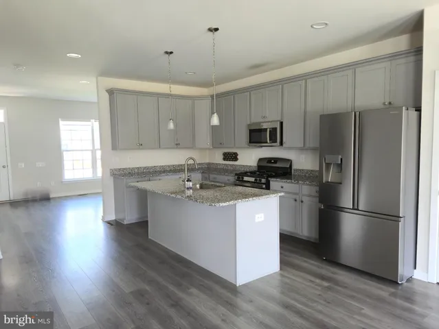 a kitchen with stainless steel appliances granite countertop a refrigerator a stove a sink dishwasher and a refrigerator with wooden floor