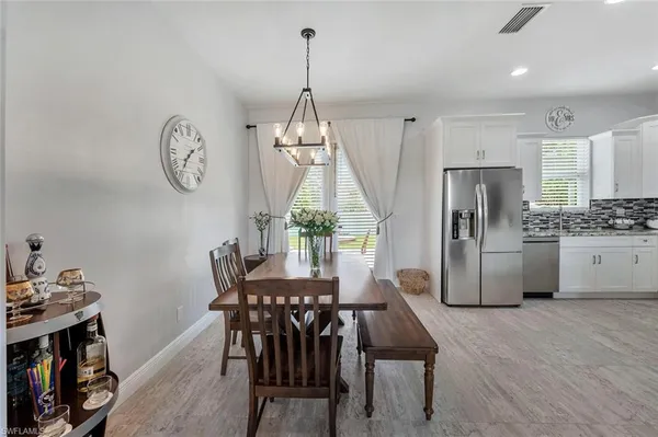 a kitchen with stainless steel appliances granite countertop a dining table chairs and a refrigerator