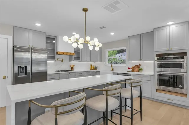 a kitchen with stainless steel appliances a dining table chairs and refrigerator