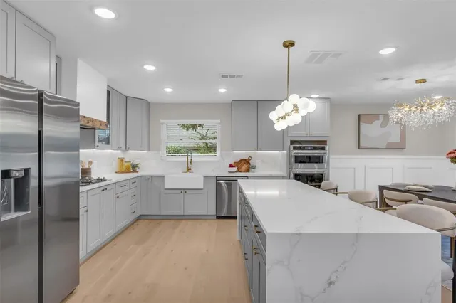 a large kitchen with white cabinets a sink a counter and stainless steel appliances