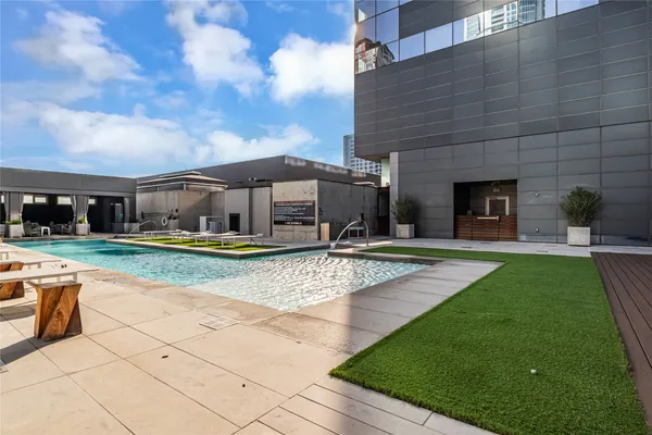 a view of swimming pool with lawn chairs and large tree