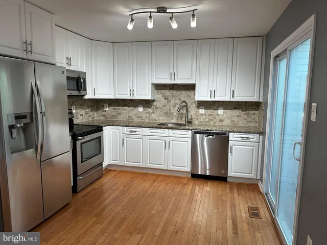 a kitchen with granite countertop white cabinets and stainless steel appliances