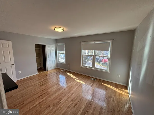 a view of an empty room with window and wooden floor