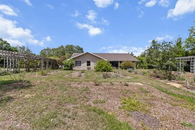 an aerial view of a house with a yard and trees all around