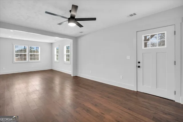a view of an empty room with wooden floor and a window