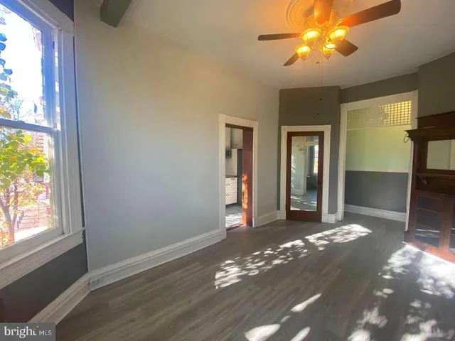 a view of an empty room with window and wooden floor
