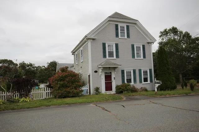 a front view of a house with a yard and trees