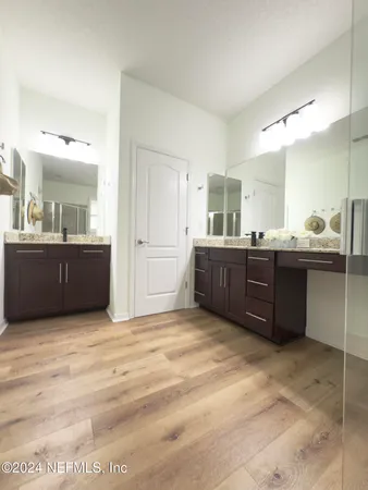 a bathroom with a granite countertop bathtub shower sink vanity mirror and toilet