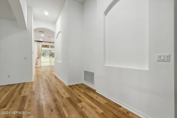 a view of an empty room with window and wooden floor
