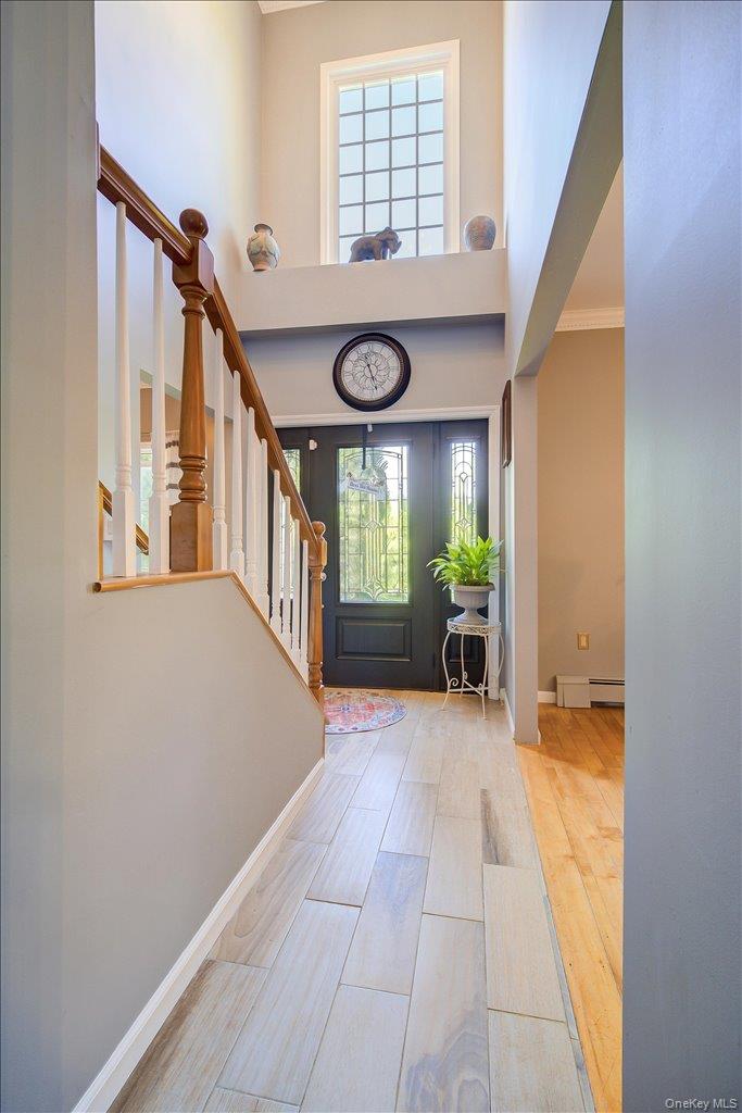 104 Wiccopee Road Putnam Valley, NY 10579 - Photo 4 of 50 Two-story foyer featuring light wood-finish flooring, a grand staircase with wood newel posts and balusters, and a front entry door with decorative glass inserts