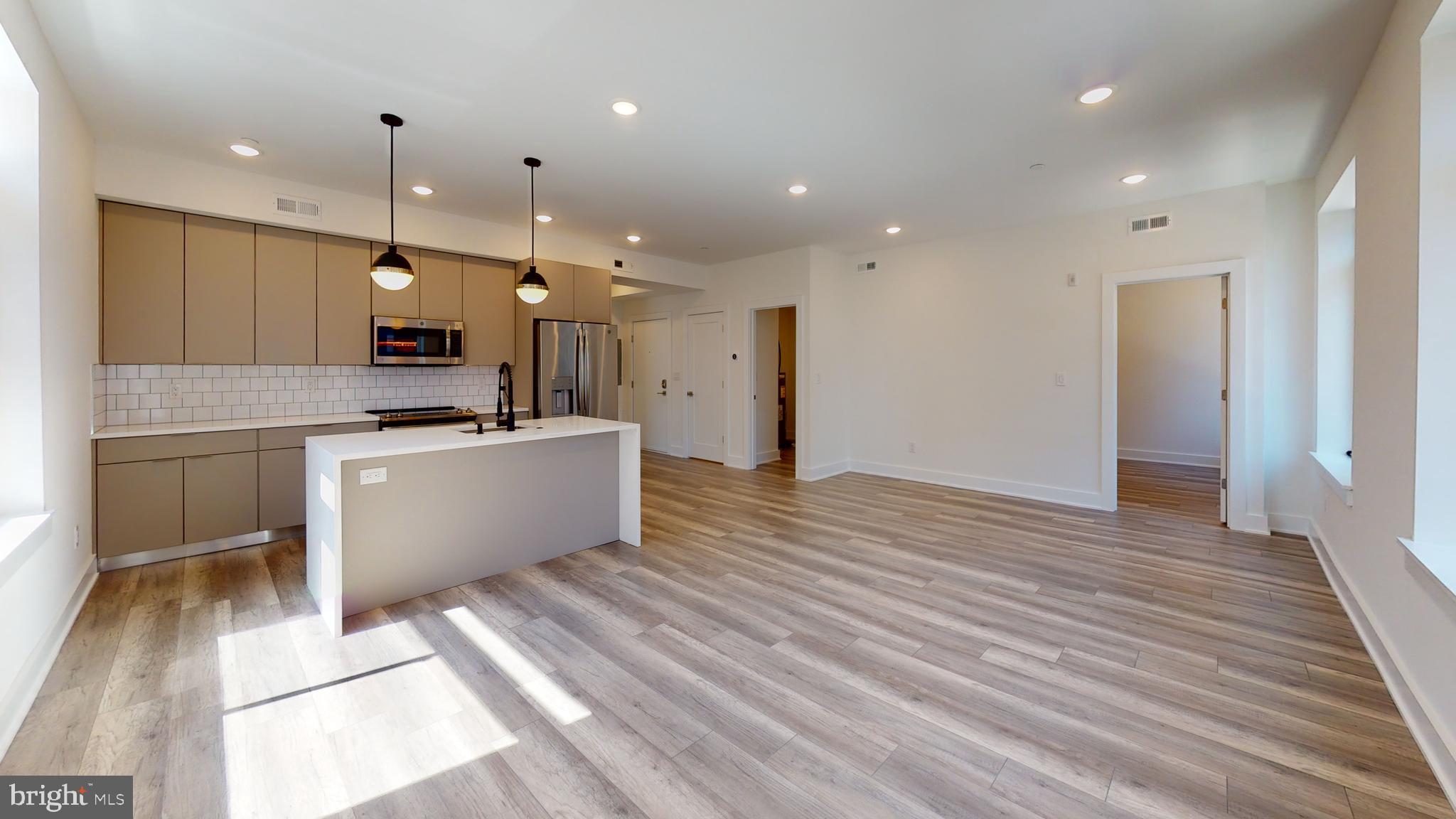 a kitchen with stainless steel appliances kitchen island granite countertop a sink and a refrigerator