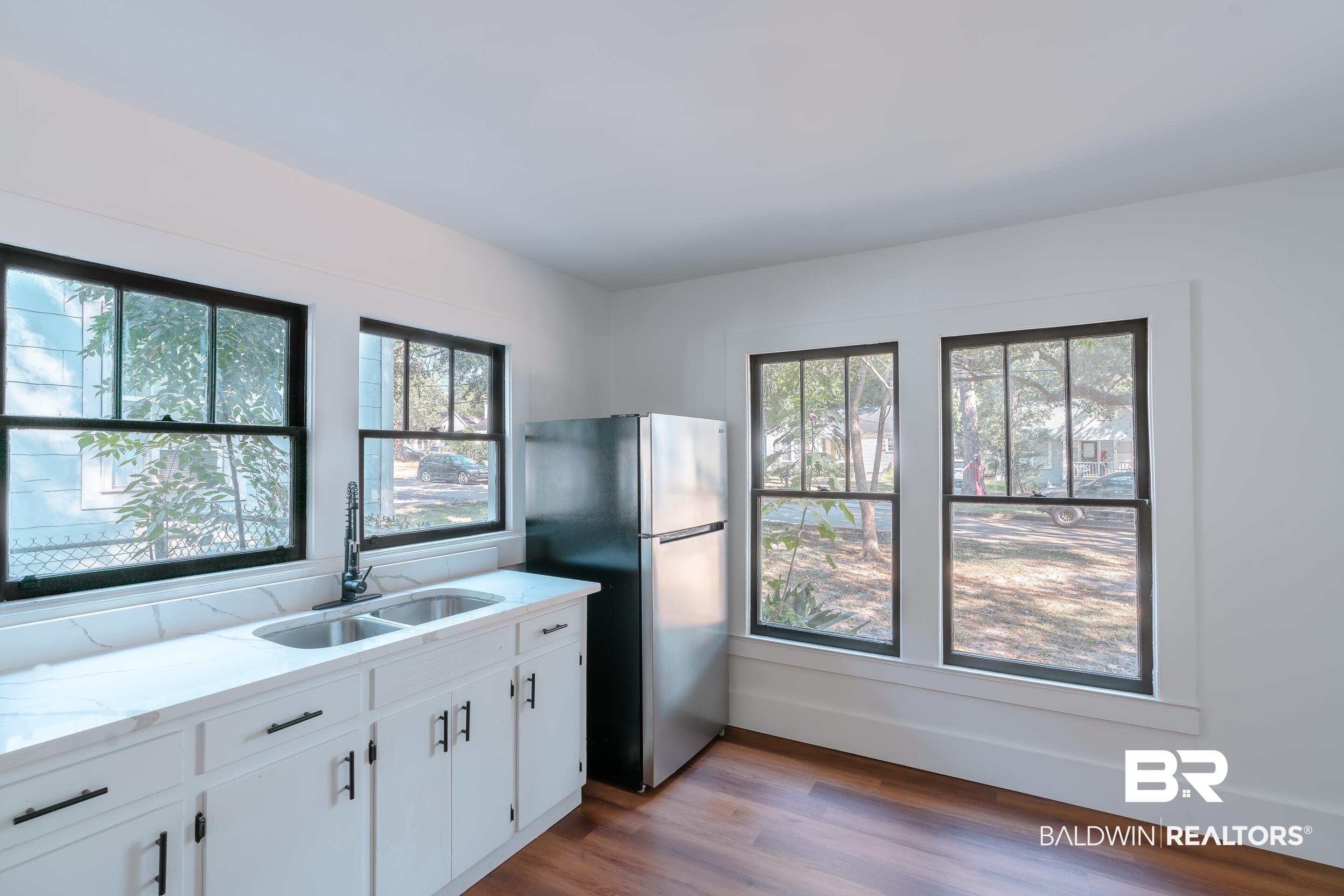 166 Crenshaw Street Mobile, AL 36606 - Photo 7 of 24 Kitchen with stainless steel refrigerator, a wealth of natural light, and white cabinets