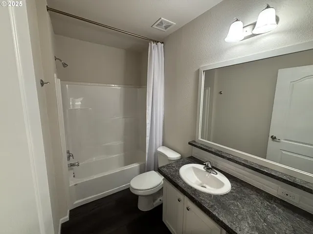 a bathroom with a granite countertop sink toilet a mirror and shower