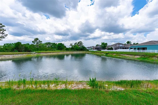a view of a lake with a big yard and large trees