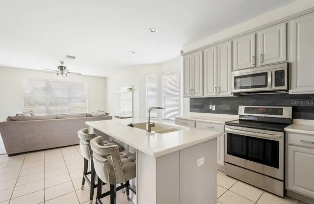 a kitchen with kitchen island granite countertop a stove a sink and a microwave
