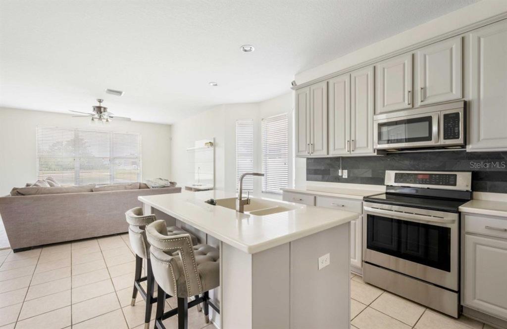 3533 Juneberry Drive Wesley Chapel, FL 33543 - Photo 5 of 12 a kitchen with kitchen island granite countertop a stove a sink and a microwave