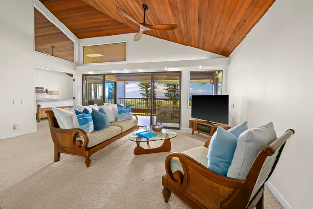 a living room with furniture a flat screen tv and floor to ceiling window