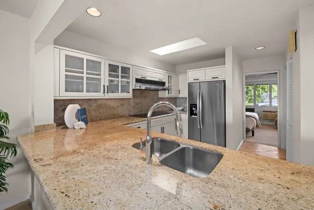 a kitchen with granite countertop a refrigerator and a sink