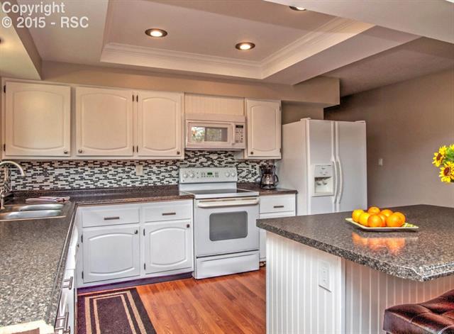 Open kitchen with white cabinets and appliances. Upgraded counter tops with wood flooring. Great for entertaining.