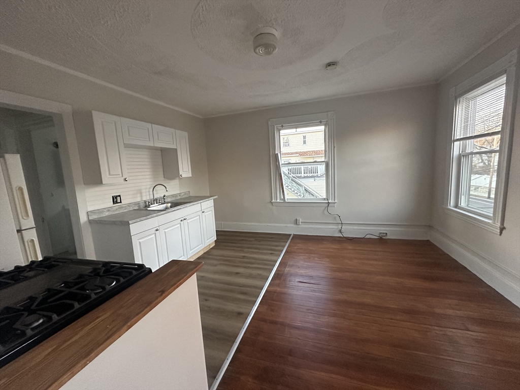 26 North Main Street, Unit 4 Natick, MA 01760 - Photo 2 of 13 a kitchen with stainless steel appliances granite countertop a stove a sink and white cabinets with wooden floor