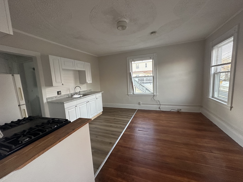 26 North Main Street, Unit 4 Natick, MA 01760 - Photo 4 of 13 a kitchen with stainless steel appliances a stove and white cabinets with wooden floor