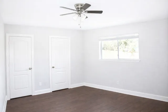 an empty room with windows and fan