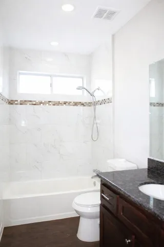 a bathroom with a granite countertop sink a toilet and bathtub
