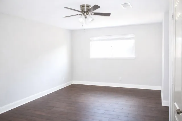 a view of a room with wooden floor and a ceiling fan