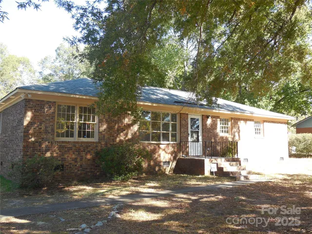 a view of a brick house next to a yard with potted plants