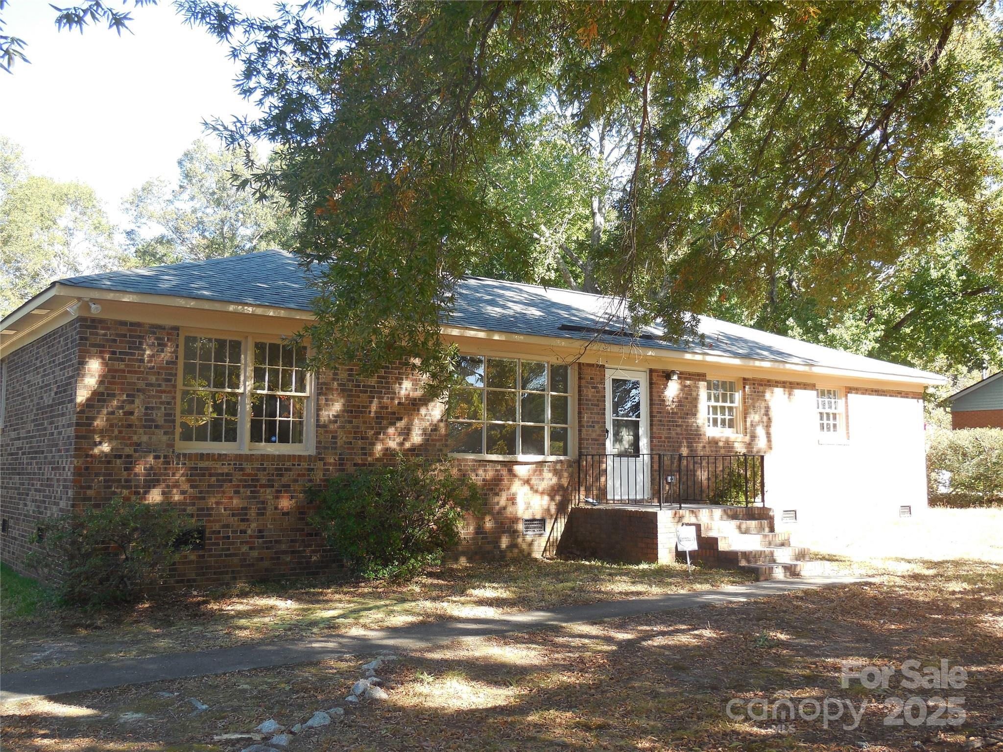 a view of a brick house next to a yard with potted plants
