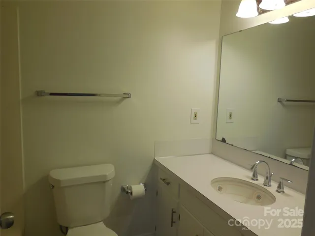 a bathroom with a granite countertop sink toilet and a mirror