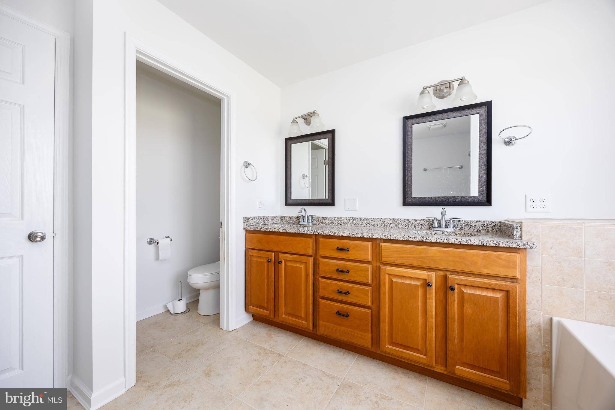 111 Sunset Circle, Unit 111E Crisfield, MD 21817 - Photo 45 of 57 a bathroom with a granite countertop double vanity sink mirror and toilet