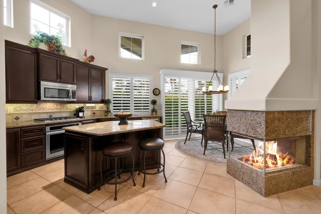 a kitchen with stainless steel appliances granite countertop a stove top oven a sink dishwasher a dining table and chairs with wooden floor