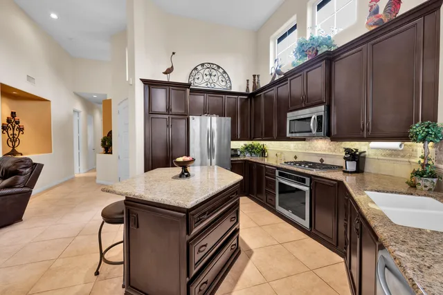 a kitchen with kitchen island granite countertop a sink stove and cabinets