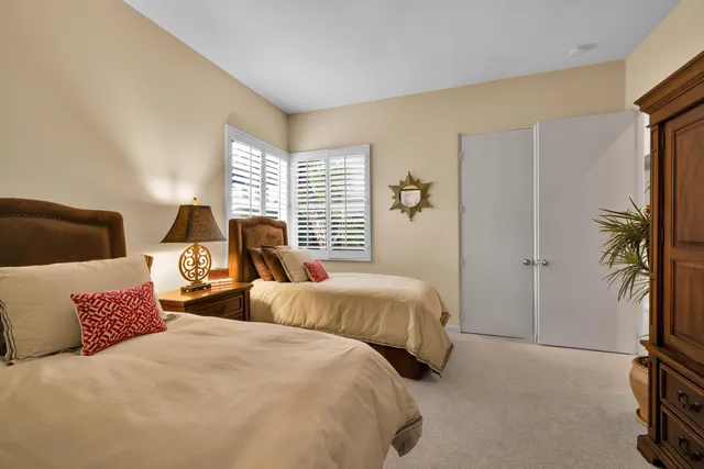 a bedroom with two bed and a potted plant