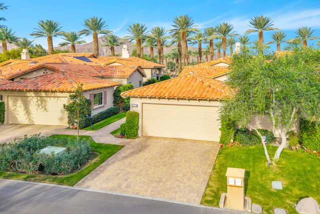 a view of yellow house with palm trees