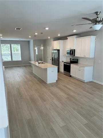 a large kitchen with stainless steel appliances kitchen island a large counter top and a wooden floors