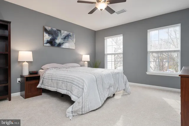 a spacious bedroom with a bed painting on wall and windows