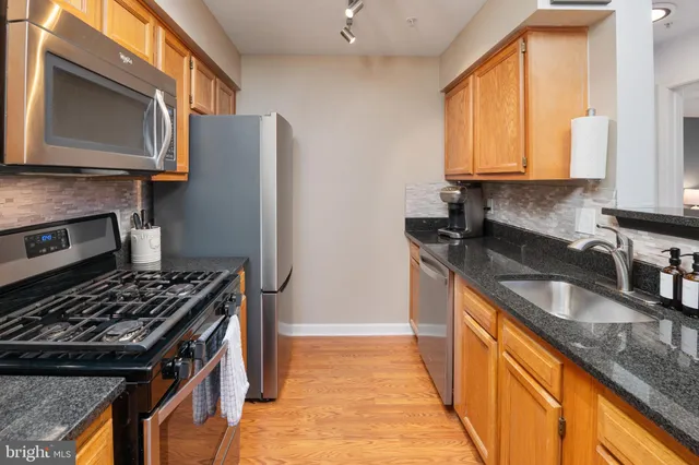 a kitchen with granite countertop stainless steel appliances a sink stove and refrigerator